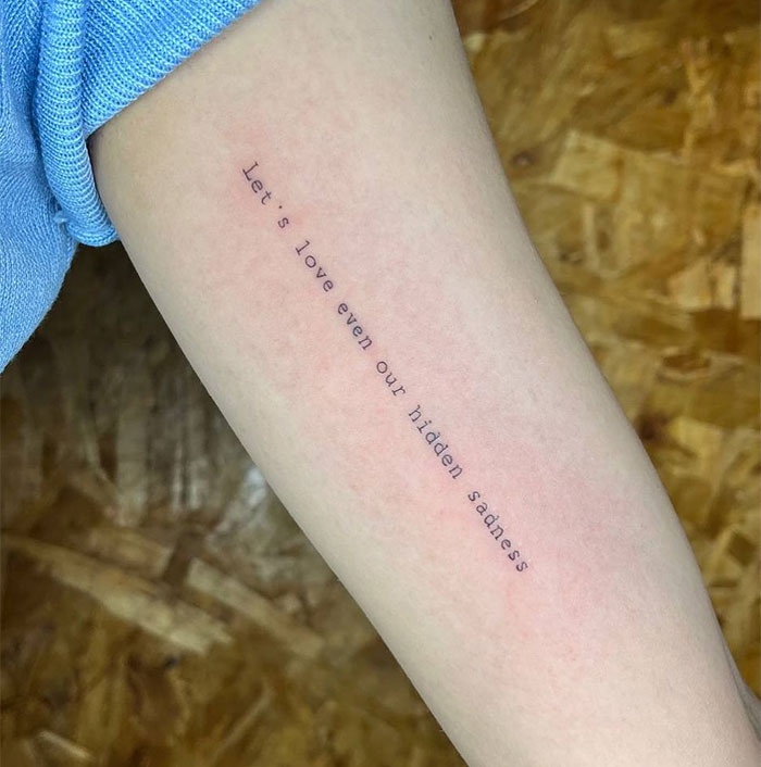 Small tattoo with a quote on an arm, capturing meaningful expression.