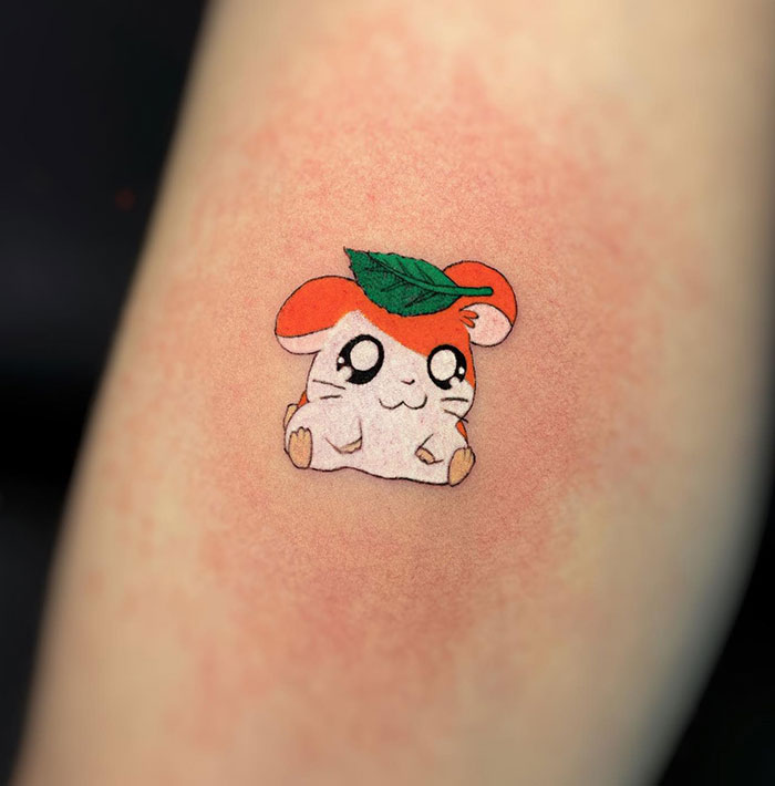 Cute small tattoo of a cartoon hamster with leaf hat, showcasing creative tattoo ideas.