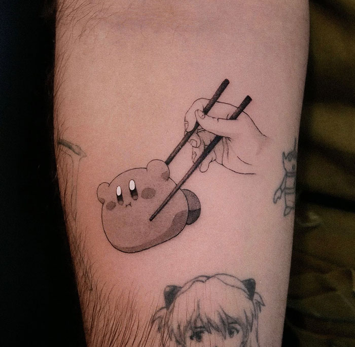 Small tattoo of a cute character being picked up with chopsticks on an arm.