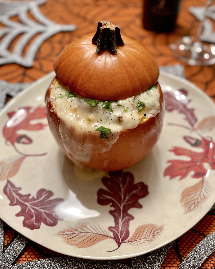 Pumpkin stuffed with creamy cheesy dip garnished with herbs, a creative Halloween snack idea nailed perfectly.
