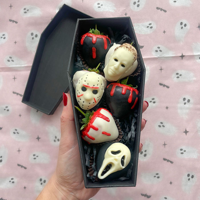 Halloween snacks shaped like horror movie characters on chocolate-covered strawberries in a coffin-shaped box.