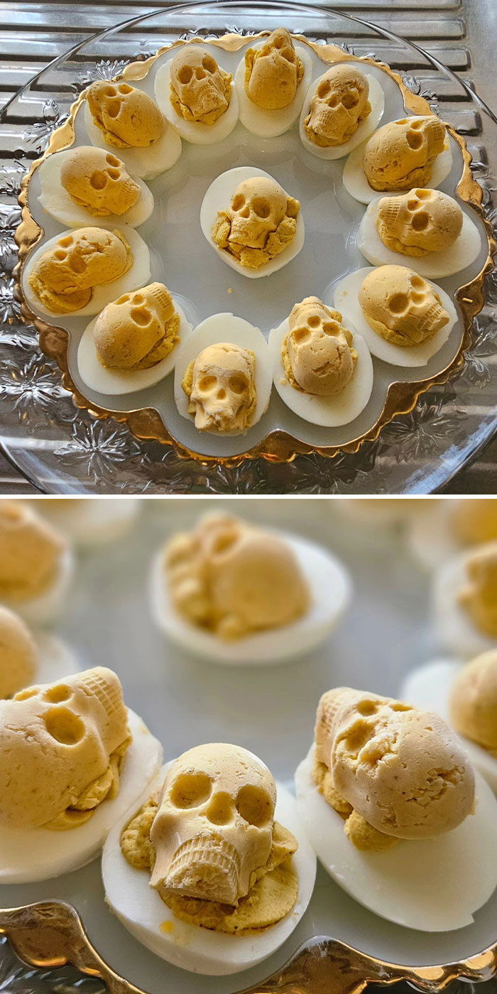 Halloween snacks featuring deviled eggs decorated with detailed skull-shaped toppings on a decorative glass platter.