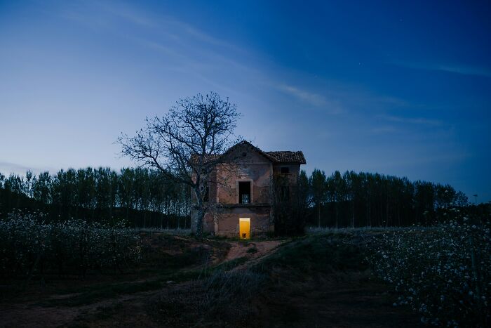 Old abandoned house with a glowing door at dusk surrounded by trees illustrating fear and hatred after first experience.