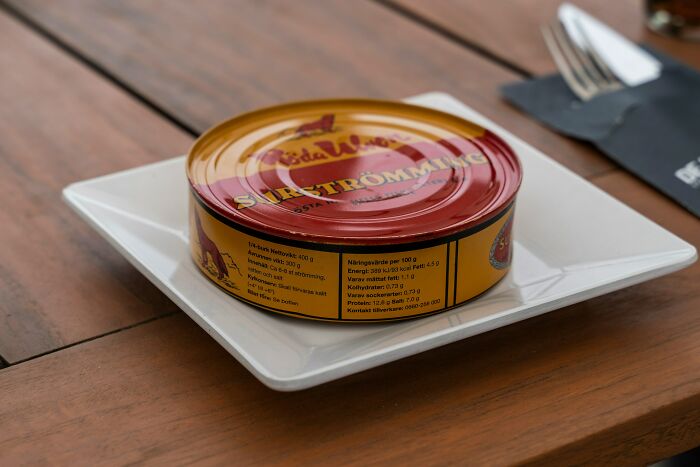 Can of surströmming on a plate, illustrating a common food people develop hatred for after trying once.