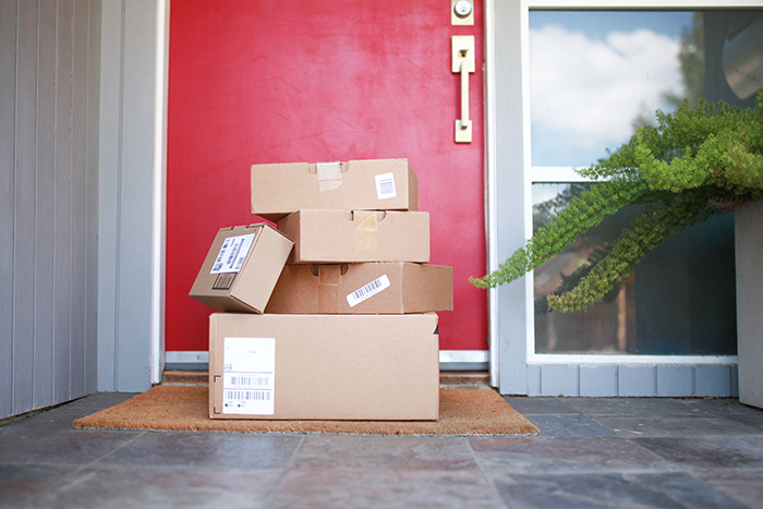 Several packages stacked on a doorstep, illustrating shopaholic tenants' deliveries.