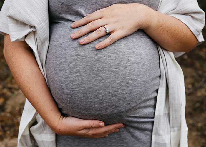 Pregnant woman cradling her belly, contemplating baby names and societal perceptions of bullying. Pregnant woman cradling her belly, contemplating baby names and societal perceptions of bullying.