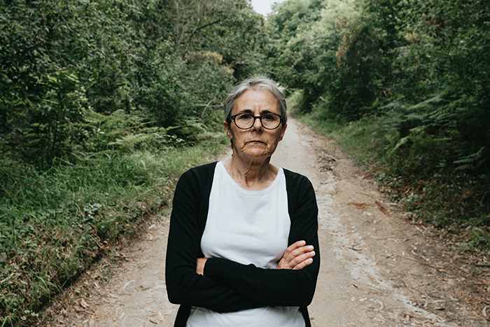 Elderly woman in a forest scene, arms crossed, contemplating a family proposal involving her future grandchild. Elderly woman in a forest scene, arms crossed, contemplating a family proposal involving her future grandchild.