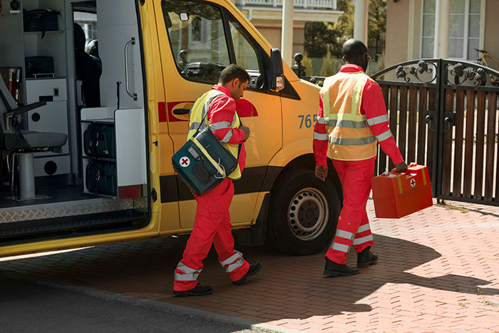 Paramedics carrying medical kits near an ambulance, ready to assist a bleeding employee. Paramedics carrying medical kits near an ambulance, ready to assist a bleeding employee.