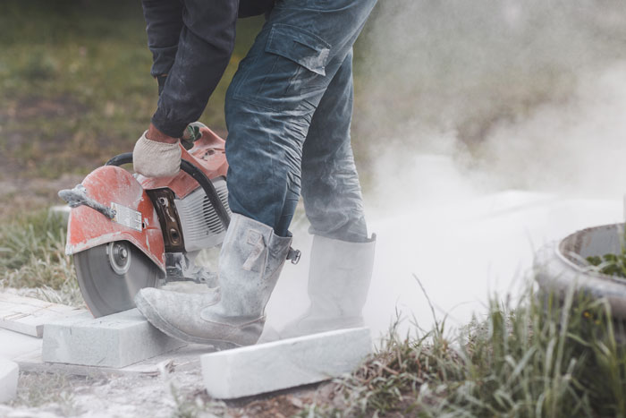 Person cutting bricks with a circular saw, illustrating working too fast, surrounded by dust. Person cutting bricks with a circular saw, illustrating working too fast, surrounded by dust.