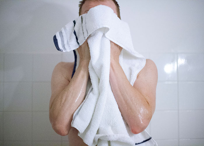 Person drying face with a towel in a bathroom, illustrating a reason leading to divorce.