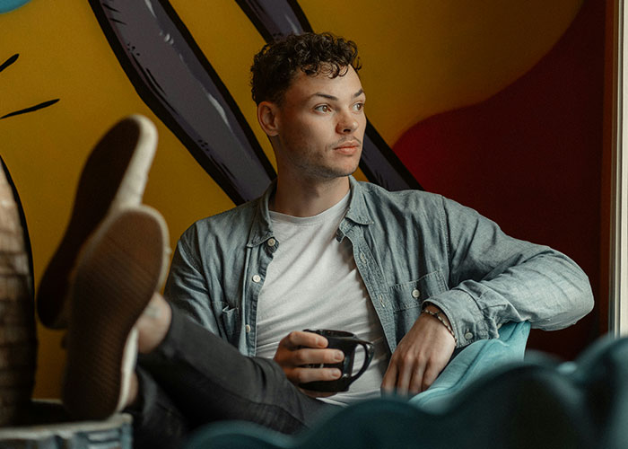 Man in casual attire sitting with a coffee cup, contemplating struggles men wish women knew.