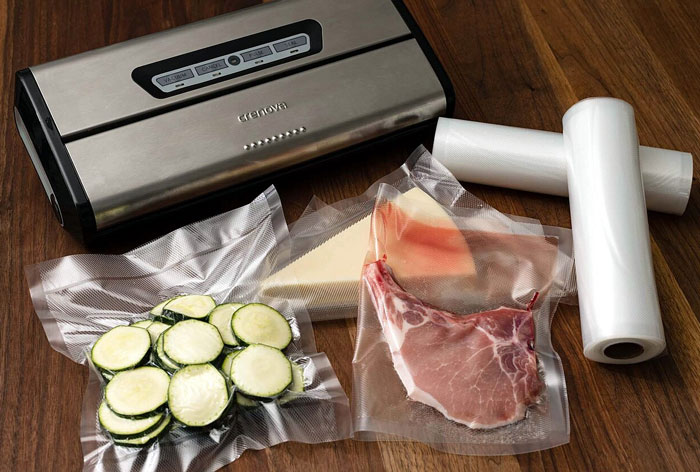Vacuum sealer with sealed food items, illustrating frugal choices for food preservation on a wooden surface.