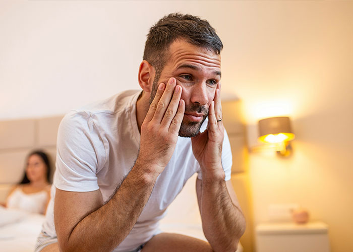 Man looking frustrated in a bedroom setting, possibly reacting to a savage insult.