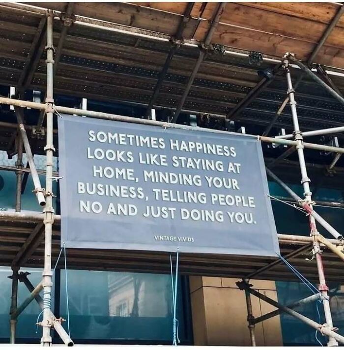 Sign on scaffolding with a relatable quote about staying home and minding your own business.