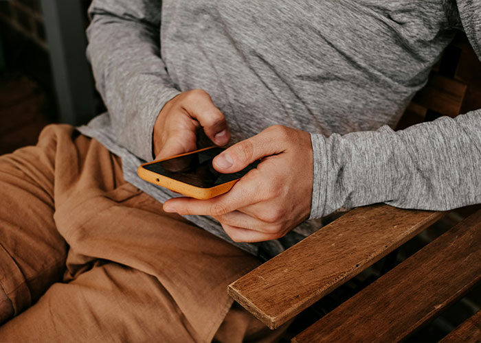 Person in a gray shirt sitting and holding a smartphone, symbolizing understandable reasons behind marital divorce.