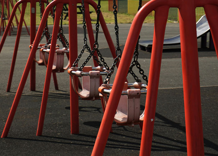 Empty playground swings set under a cloudy sky, illustrating a visual metaphor for savage insults.