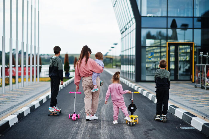 Family on scooters outside a modern building, experiencing reverse culture shock.