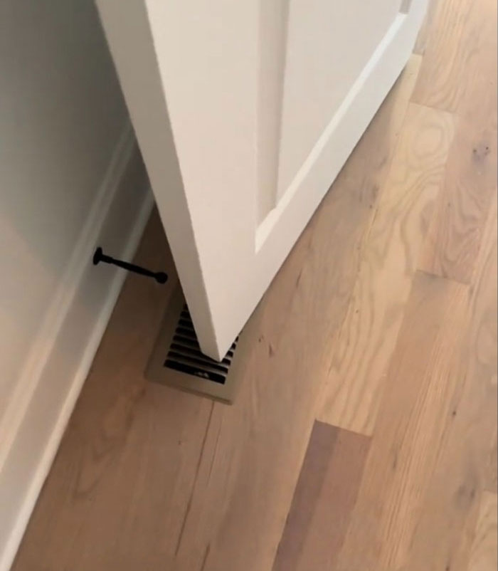 White door in $1,600,000 home built 2 years ago showing flawed construction with misaligned placement over floor vent.