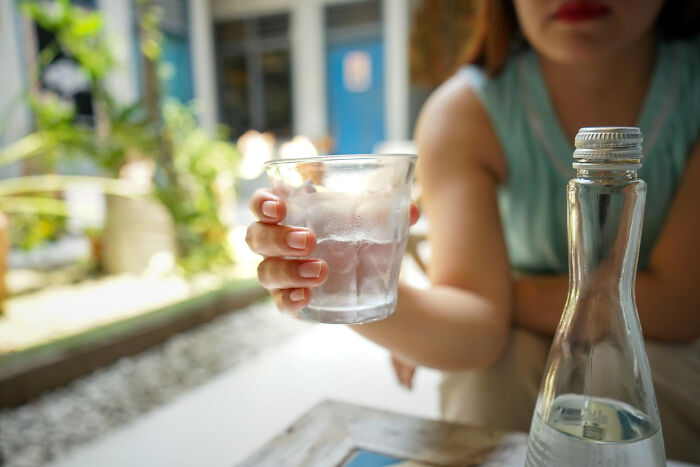 A woman holds a glass of water, depicting reverse culture shock for Americans who lived abroad.