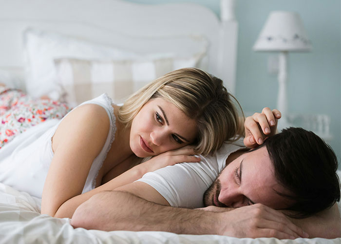 A couple lying in bed, woman looks thoughtful, highlighting struggles men wish women knew.