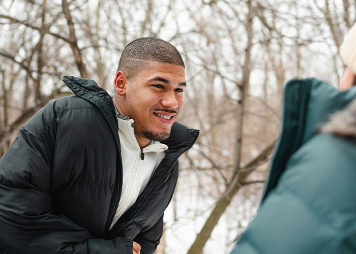 Man in winter jacket smiling during a conversation outdoors, highlighting struggles men experience.