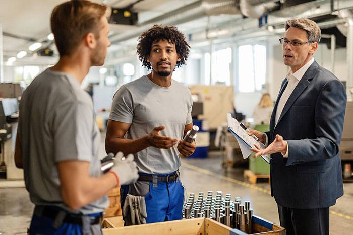 Manager discussing input with two factory workers, emphasizing communication and teamwork. Manager discussing input with two factory workers, emphasizing communication and teamwork.