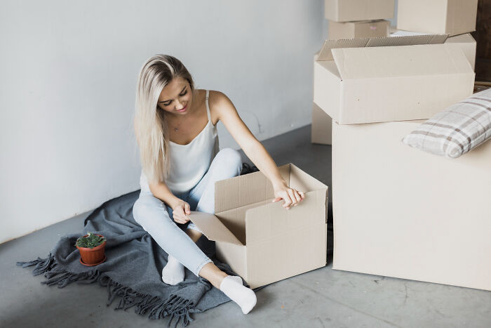 Woman in casual wear unpacking boxes surrounded by moving supplies, illustrating a risky decision outcome.