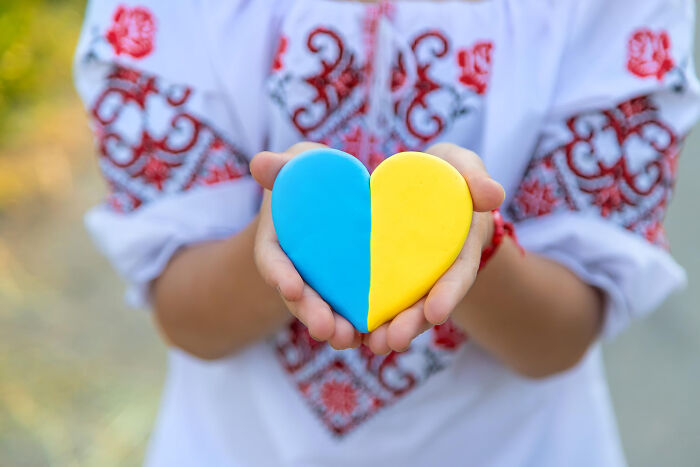 Hands holding a heart in blue and yellow, symbolizing country pride amidst fears.