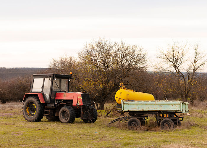 Tractor on a field with bare trees and equipment, symbolizing a farmer's defiance to HOA demands.