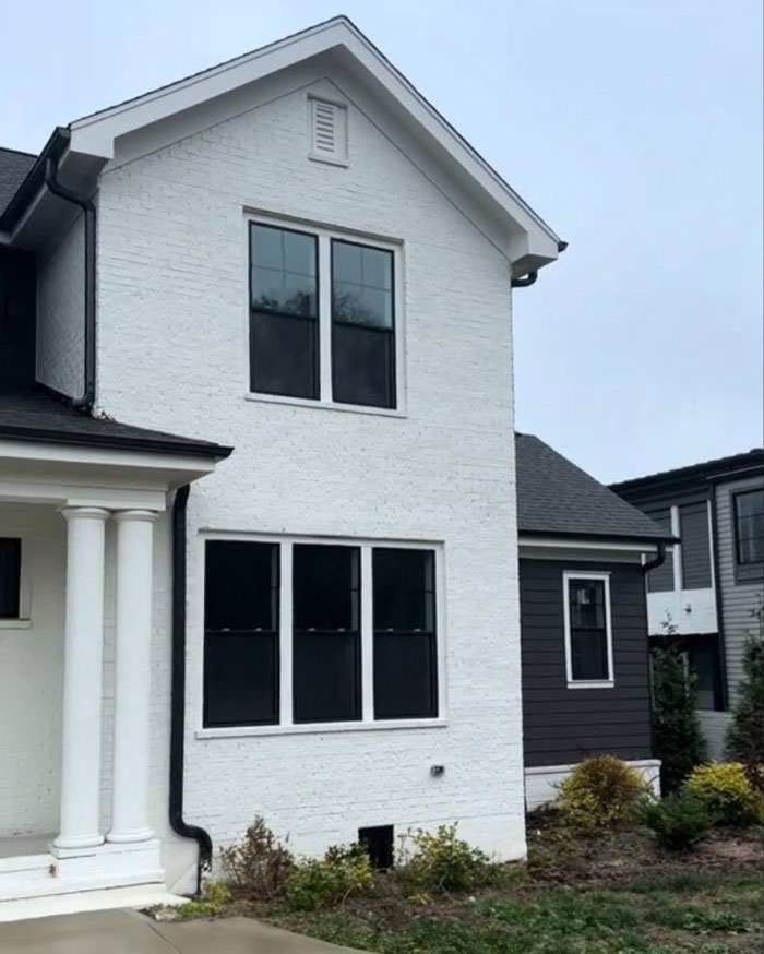 $1,600,000 home exterior with white brick, two-story facade, columns, and windows, built 2 years ago.