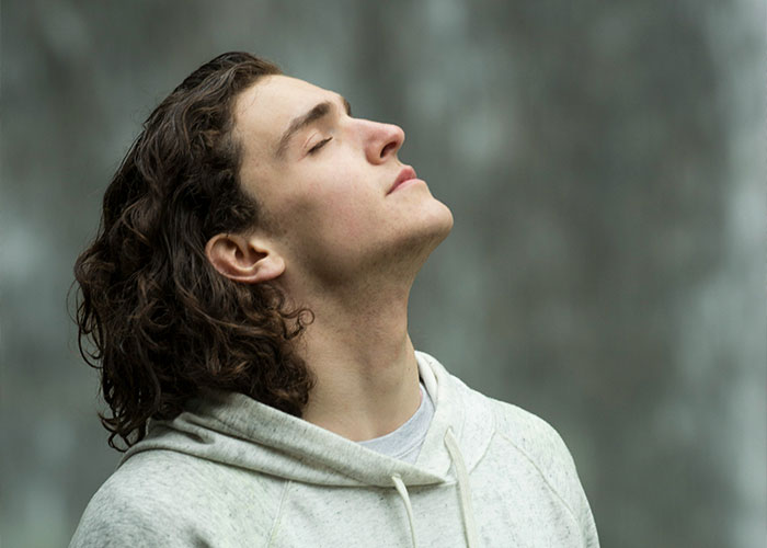 Man in a hoodie with eyes closed, representing struggles men wish women knew.