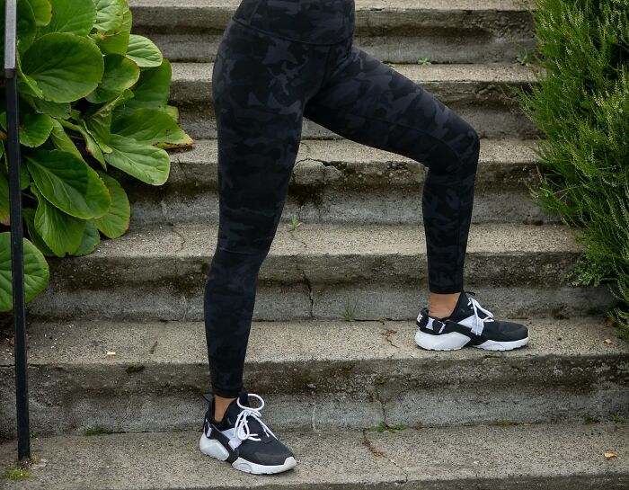 Person in black camo leggings and sneakers on stone steps, showcasing trust and confidence.