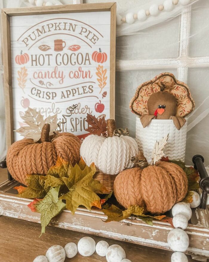 Thanksgiving home decor with knitted pumpkins, a turkey plushie, and a festive sign featuring autumn treats.