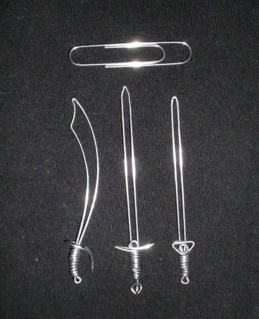Miniature swords crafted from paper clips on black fabric, showcasing cool creativity.