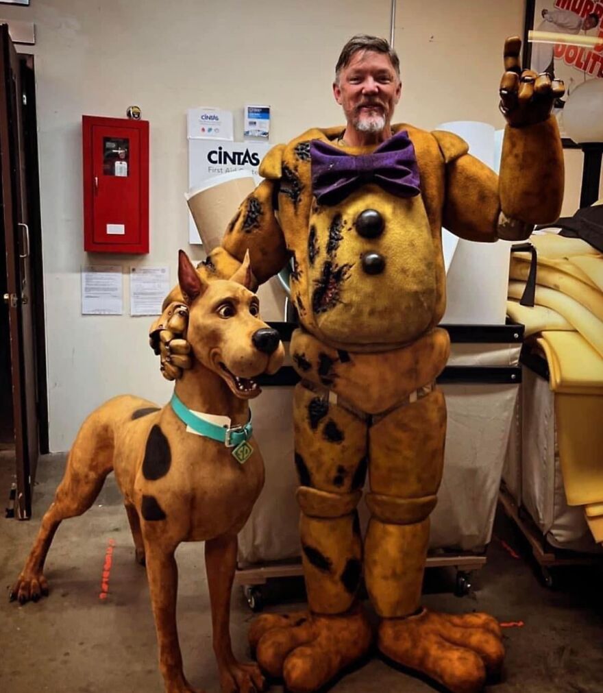 Man in a bear costume with a lifelike Scooby-Doo model, capturing pics that go hard in a creative setting.