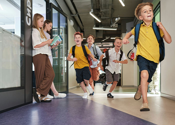 Children running in a school hallway, wearing backpacks and smiling, highlighting the theme of cruelty and bullying. Children running in a school hallway, wearing backpacks and smiling, highlighting the theme of cruelty and bullying.