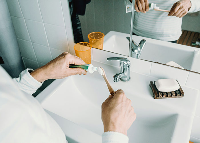 Person squeezing toothpaste onto a toothbrush over a bathroom sink, a relatable marriage moment.