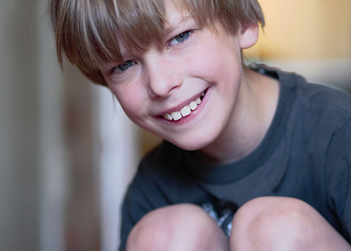 Smiling child wearing a dark shirt, capturing a playful moment, related to savage insults.