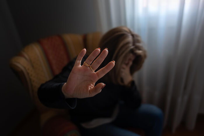 A person sitting in an armchair holds up their hand in a stop gesture, highlighting societal double standards.