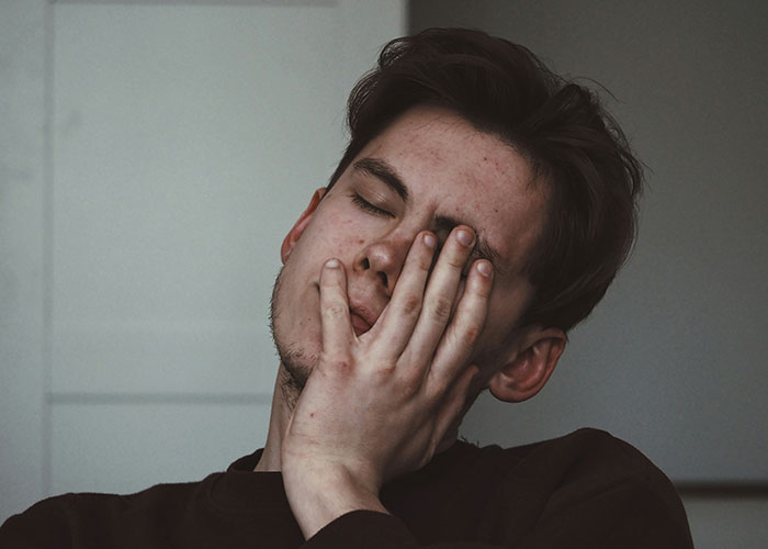 A man expressing frustration, his hand covering part of his face, illustrating struggles men wish women knew.