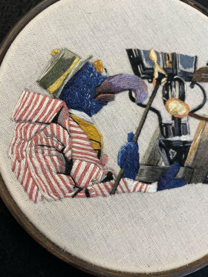 Detailed embroidery design of a colorful bird wearing a striped jacket and hat, showcasing beautiful embroidery designs.