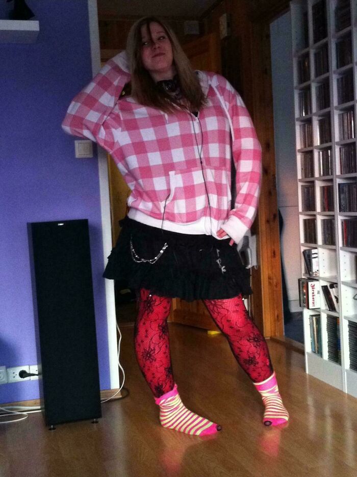 Person in mismatched outfit, including a pink checkered hoodie and colorful socks, depicting a "blunder years" fashion choice.