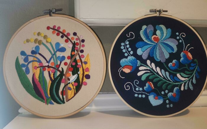 Two colorful embroidery designs in wooden hoops, showcasing detailed floral and abstract stitch patterns on fabric.