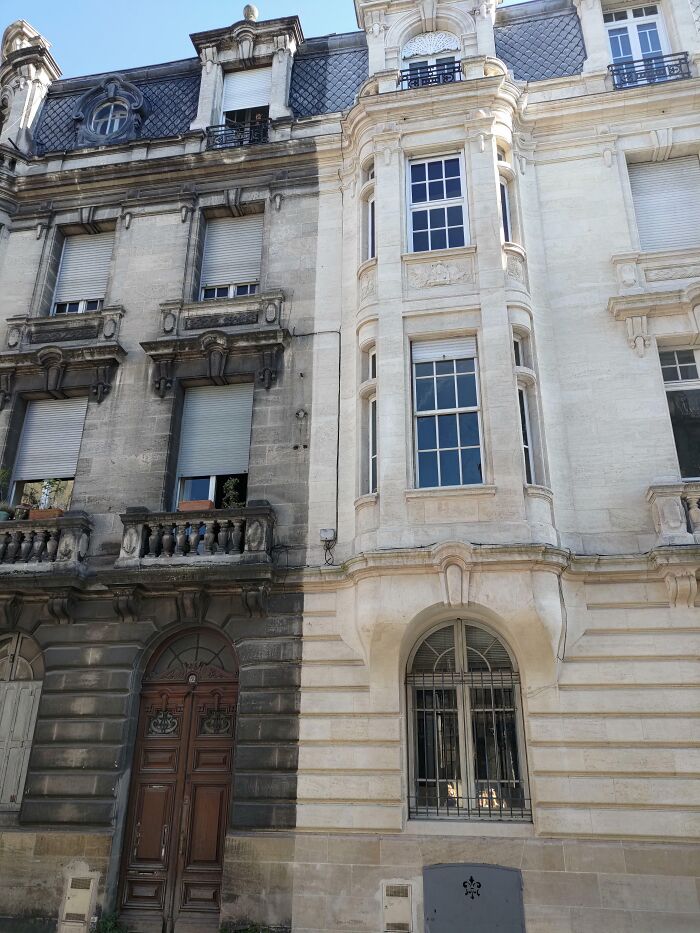 Old building facade shows dramatic change after power washing, revealing clean, bright stonework on the right half.