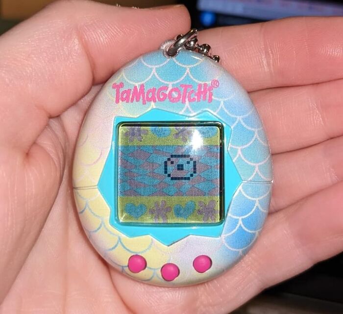 Hand holding a pastel Tamagotchi digital pet, a popular gift idea for shopping for a 12-year-old.