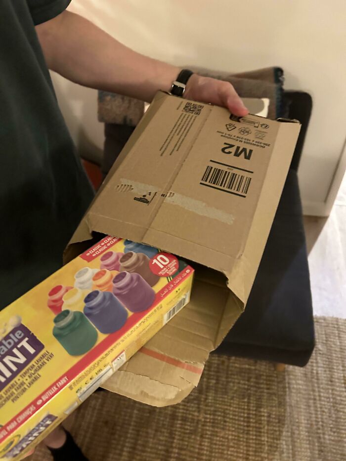 Online shopping fail: oversized cardboard box with child's paint set spilling out.