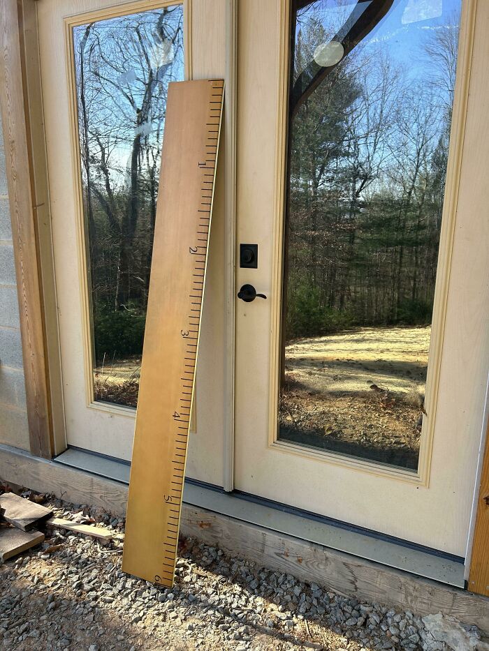 Oversized wooden ruler leaning on a glass door, illustrating online shopping fails.