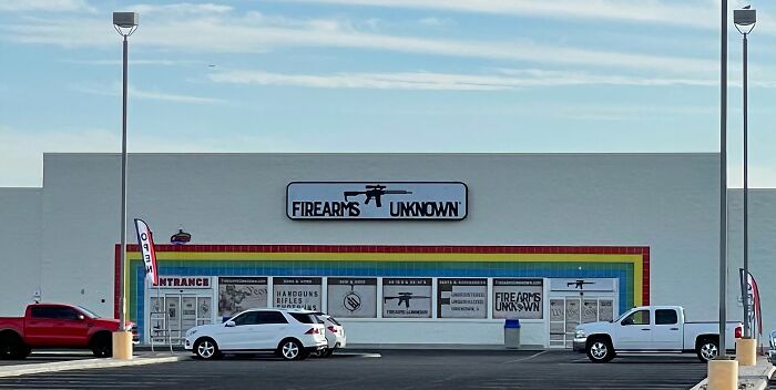 Building conversion featuring a repurposed storefront now named "Firearms Unknown" with colorful trim and parked cars.