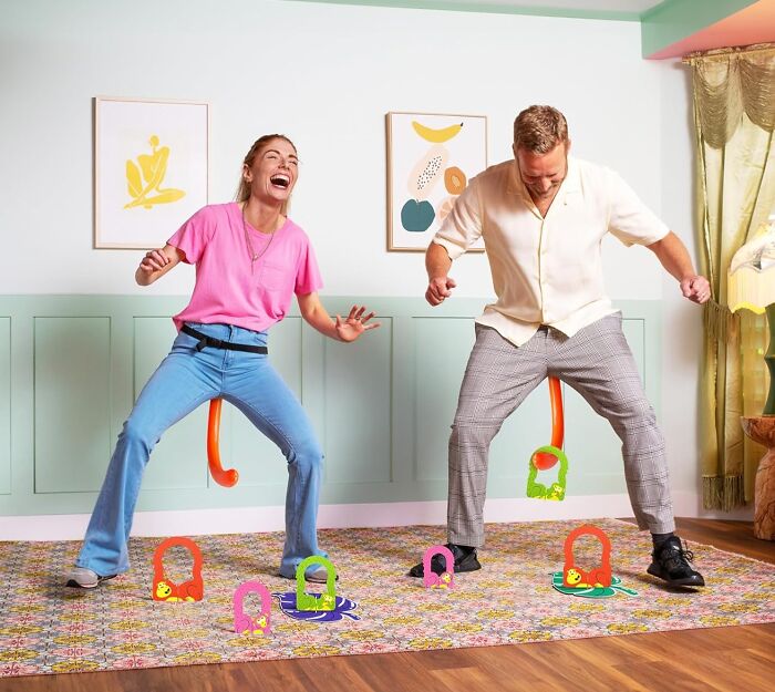 Two people playing compact and straightforward games indoors, laughing and having fun in a colorful room.