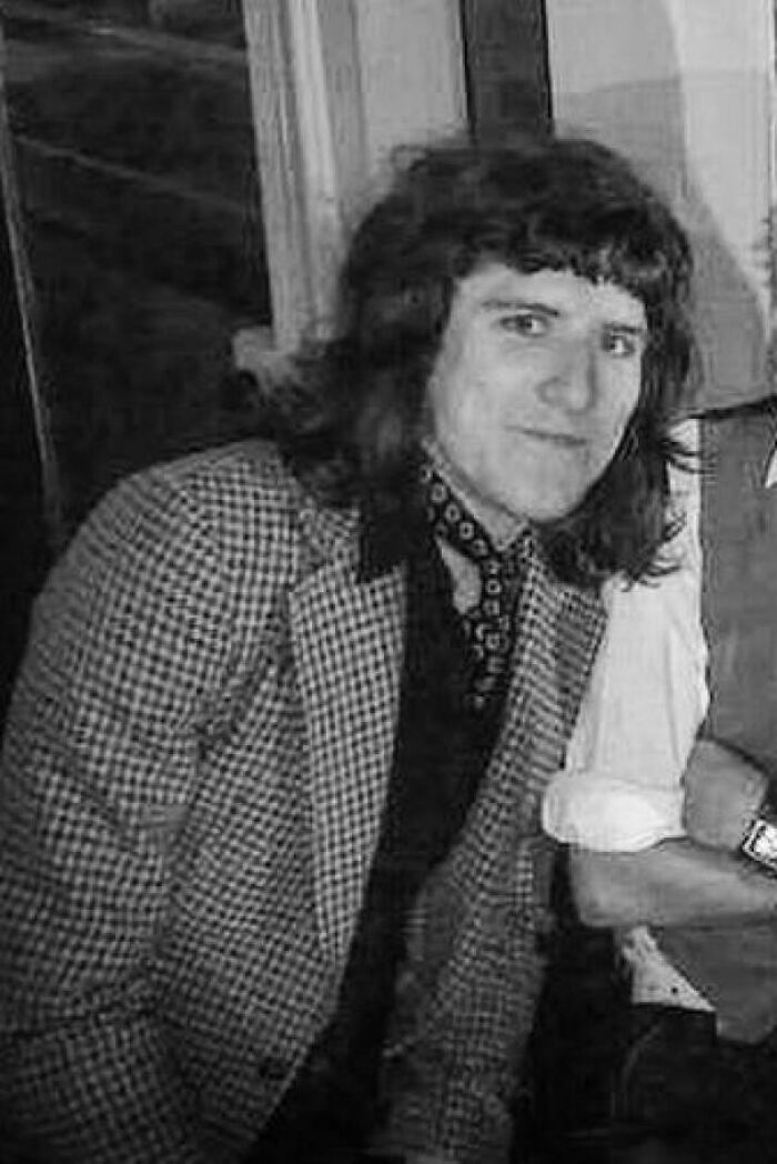 Person in vintage plaid jacket with long hair smiling awkwardly, representing a blunder year style moment.